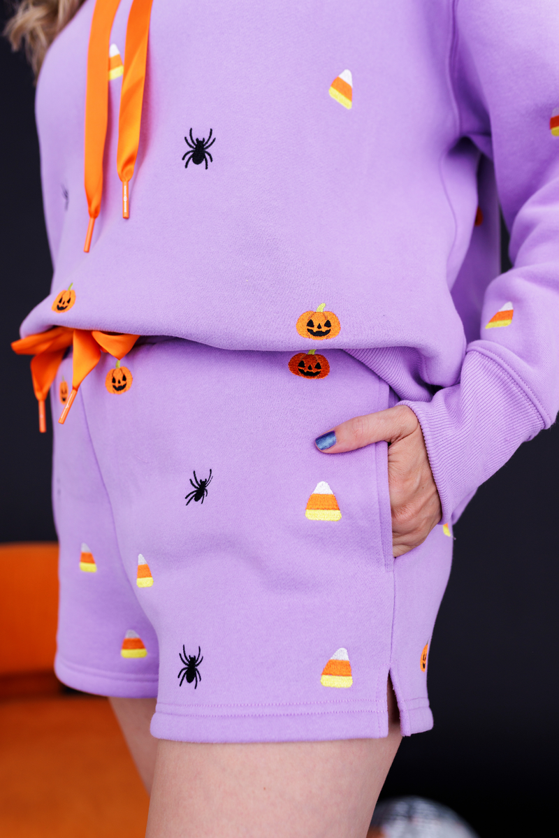 Model wearing the Lavender Spooky Fleece Shorts with embroidered spiders and candy corn, side view